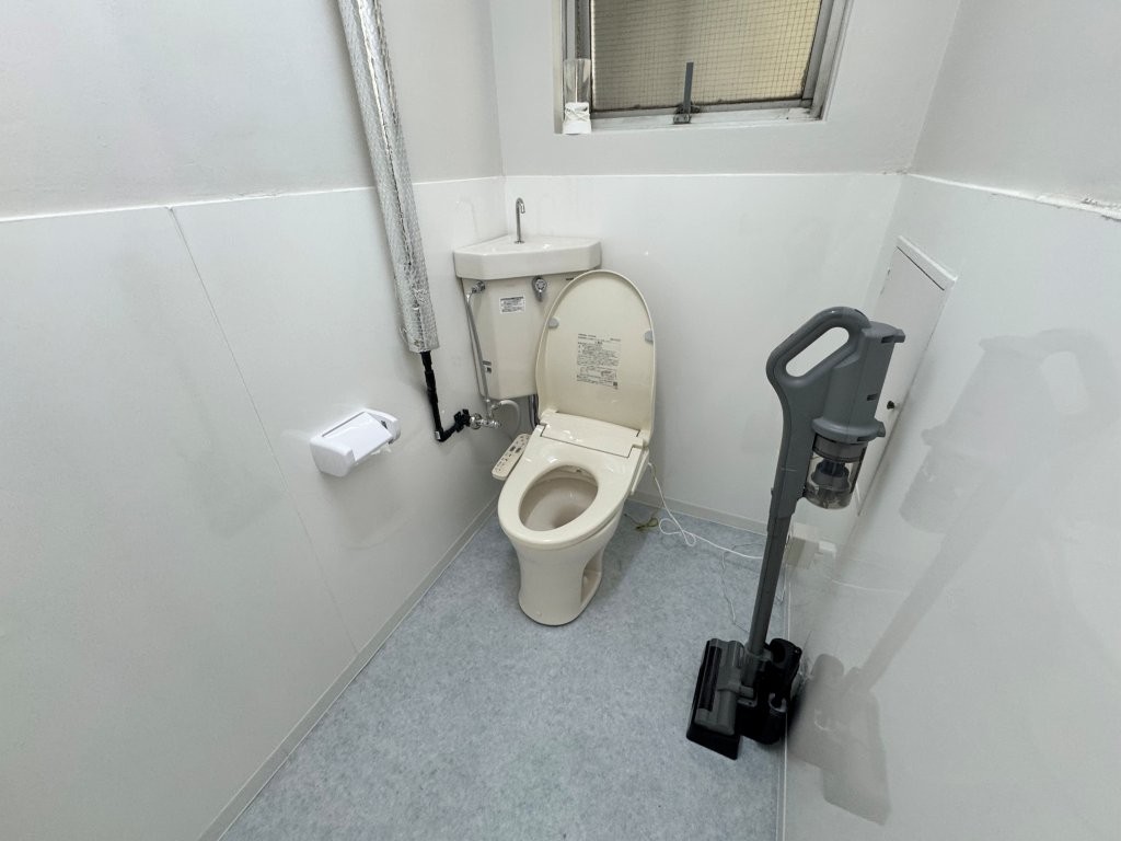 和式から洋式へ改修後のトイレ。白い壁パネルとクッションフロアで明るく衛生的に仕上がった洋式便器の施工後